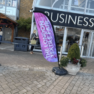 the london textile fair sign placed outside of a venue in colours pink and purple